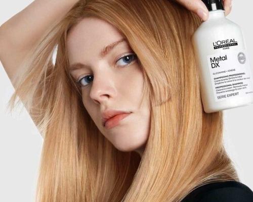 Kuva missä nainen pitää kädessään Metal DX 500ml shampoo pulloa.