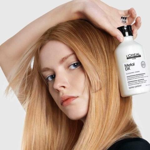 Kuva missä nainen pitää kädessään Metal DX 500ml shampoo pulloa.